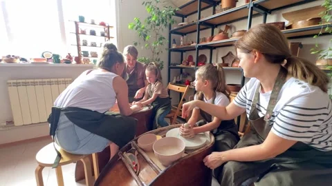 Master potter teaches children and their moms to make a clay jug Stock Footage 277793228