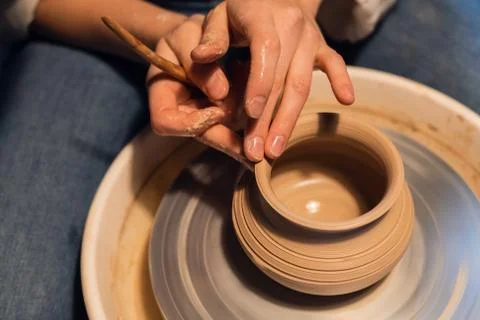 A master in a pottery workshop shows the technique of modeling a pot on a Potter Stock Photos