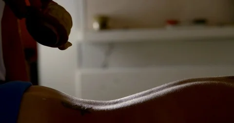 Master is pouring massaging oil on naked back of client in dark room, profile 스톡 동영상 111424924