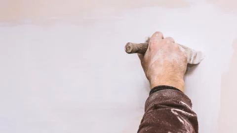 Master prime a putty wall before applying a decorative layer of plaster Stock Photos