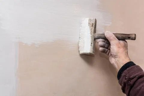 Master prime a putty wall before applying a decorative layer of plaster. Work Foto stock