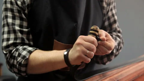 The master processes the edges on the leather strap with a special tool Stock Footage 86709016