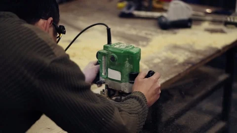 A master in protective glasses working with manual grinding machine at wood Stock Footage 121451670