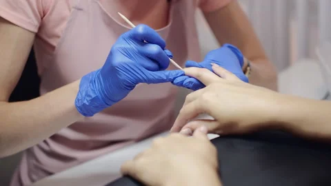 Master in protective gloves removes client cuticle in salon Stock Footage 140052905