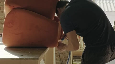 Master pulls new fabric onto the wood base. makes a armchair in the furnitur Video stock 170019390
