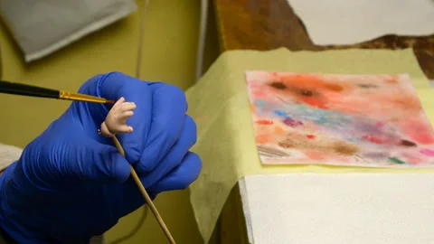 Master puppet intently paints fingers on dolls hand with thin brush. Stock Footage 128678147