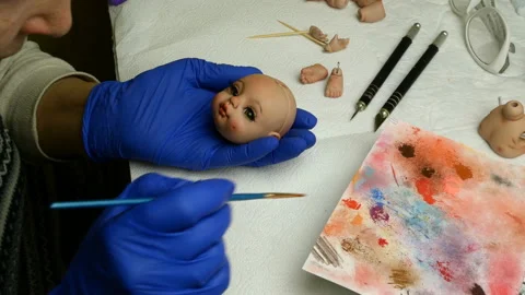 Master puppet intently paints lips of blank for doll with thin brush. Stock Footage 128681190