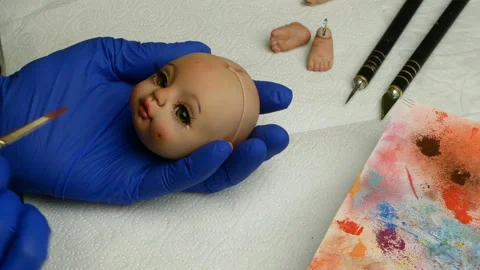 Master puppet intently paints lips of blank for doll with thin brush. Stock Footage 128682443