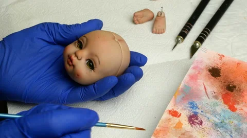 Master puppet intently paints lips of blank for doll with thin brush. Stock Footage 128683778