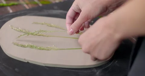 The master puts leaves for imprint on the clay board. Create handmade Stock Footage 155652666