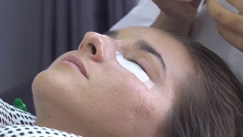 Master remove oil with cotton bud from models eye. Eyelash extension in studio. Stock Footage 75740908