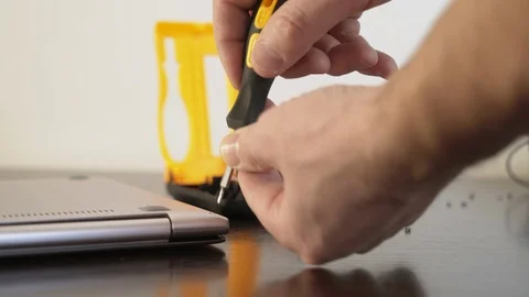 The master removes the back cover of the laptop. Hands close-up screw the screw Stock Footage 87741404
