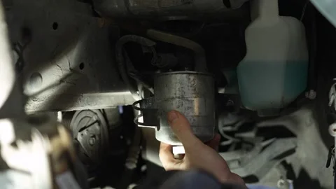 The master removes the fuel filter from the holders in the car. Home self-repair Stock Footage 320127920