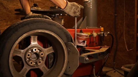 The master is removing a tire from a disk on a professional machine tool Stock Footage 114630894