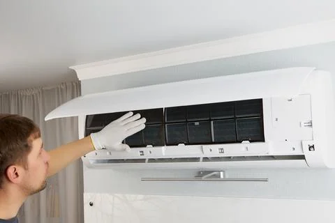 The master repairman checks the operation of the air conditioner with his hand. Stock Photos