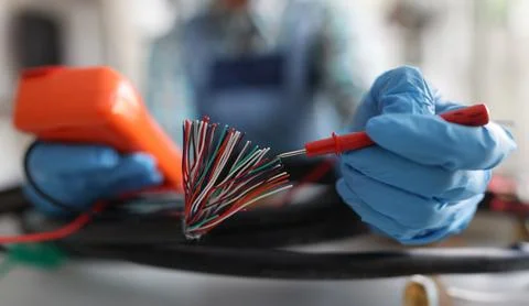 Master repairman testing multicolored wires from cable using tester closeup Stock Photos