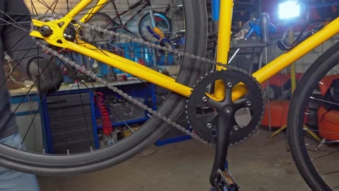 Master repairs the chain and the rear wheel on the bike. Workshop, bicycle 動画素材 193484299