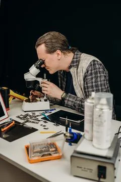 The master repairs the equipment at the table on a black background Stock Photos