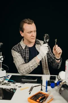 The master repairs the equipment at the table on a black background Stock Photos