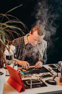 The master repairs the equipment at the table on a black background Stock Photos
