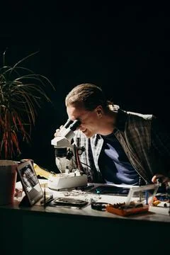 The master repairs the equipment at the table on a black background Stock Photos