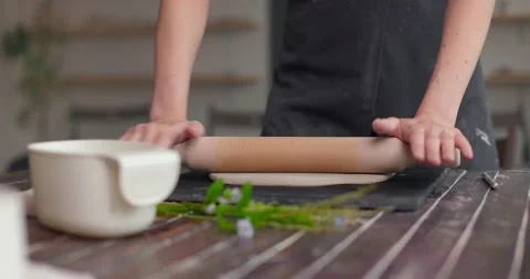 Master rolls out flatting piece of clay lying on fabric using wooden rolling pin Stock Footage 155758690