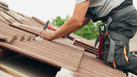 Master roofer using his hands to fix broken rooftop with hammer and nails Stock Footage 203726604