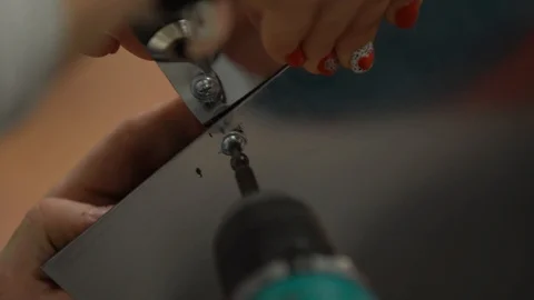 Master screws the self-tapping screw driver into a shiny plastic sheet Stock Footage 101730185