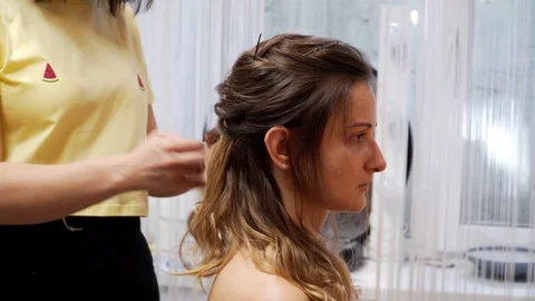 A master separates the curls and makes an evening hairstyle Stock Footage 127502611