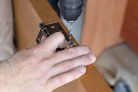 The master sets the door hinge. drills a hole with a tool Stock Photos