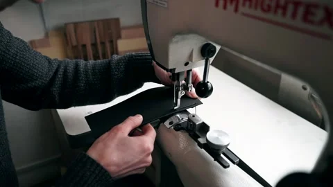 The master sews leather on a sewing machine, sewing of leather goods Stockbeeldmateriaal 151207759