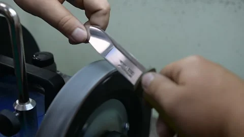 Master sharpens the knife on the machine, so it was sharp Stock Footage 92096414