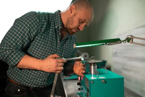 Master sharpens scissors on special equipment for sharpening tool Stock Photos