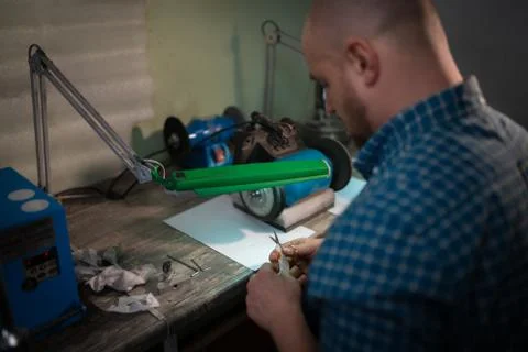 Master sharpens scissors on special equipment for sharpening tool Stock Photos