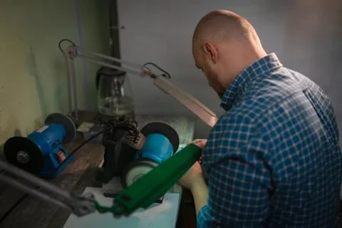 Master sharpens scissors on special equipment for sharpening tool Stock Photos