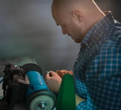 Master sharpens scissors on special equipment for sharpening tool Stock Photos
