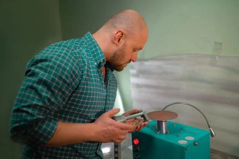 Master sharpens scissors on special equipment for sharpening tool Stock Photos