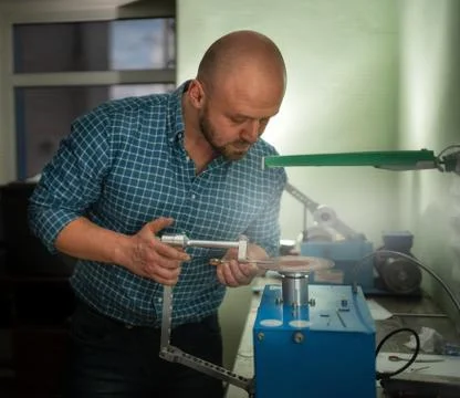 Master sharpens scissors on special equipment for sharpening tool Stock Photos