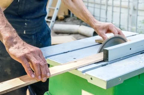 The master sharpens the wooden panel with an electric sander on a Sunny day in Stock Photos
