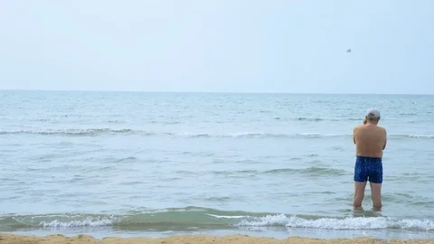 Master shot. Active senior caucasian man standing on the beach. he watches his Stock Footage 116039955