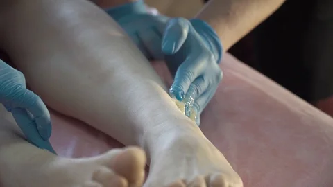Master of shugaring process of hair removal with sugar on his legs Stock Footage 87475790