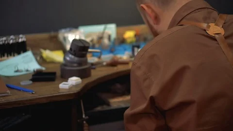 Master is sitting with his back surrounded by the tools and he is busy chores Stock Footage 73555093