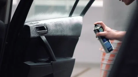 Master sprays foam on surface of door, handle of black sedan in service closeup Stock Footage 155965702