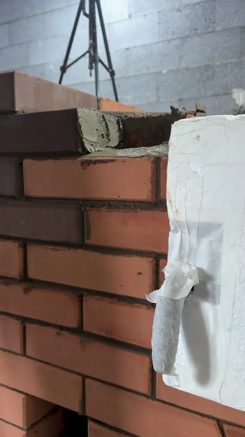 Master stove maker laying a heating stove. Placing brick and tapping with a.. Vidéo 325677235