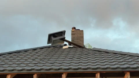 A master stove setter builds a chimney with a cap on the house roof. Heatin.. Video stock 324591530
