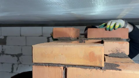 A master stove setter at work. He builds the masonry widening (flue) of a h.. Video stock 324561658