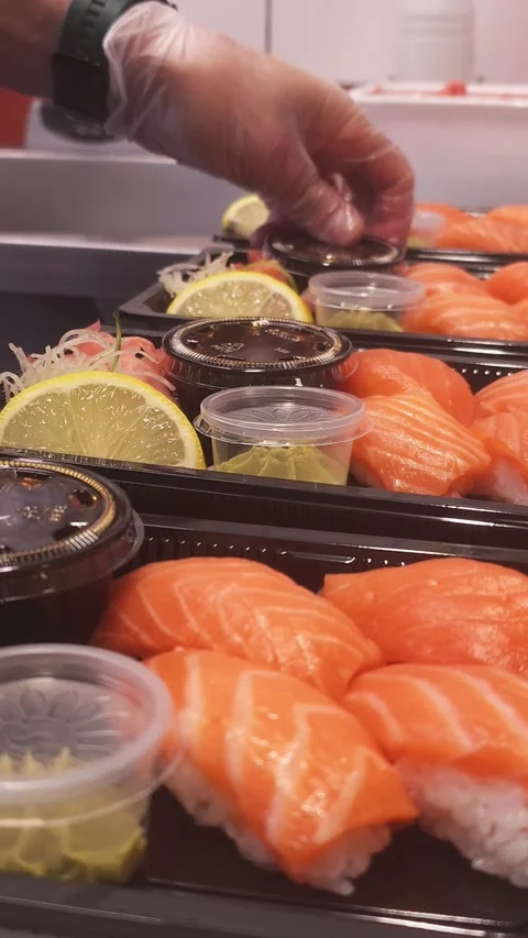 Master sushi chef carefully puts soy into small boxes alongside fresh nigiri Eac Stock Footage 285131747