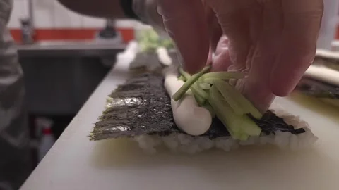 Master sushi chef expertly placing crisp cucumbers into each roll, adding a Vidéo 268741498