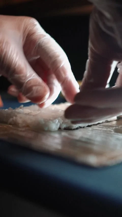 Master sushi maker makes sushi rolls from nori rice and red fish, the process of Stock Footage 256252609