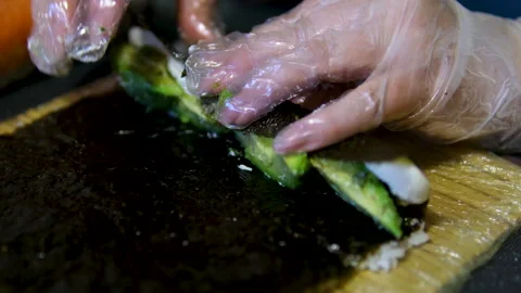 Master sushi maker makes sushi rolls from nori rice and red fish, the process of Stock Footage 302087142